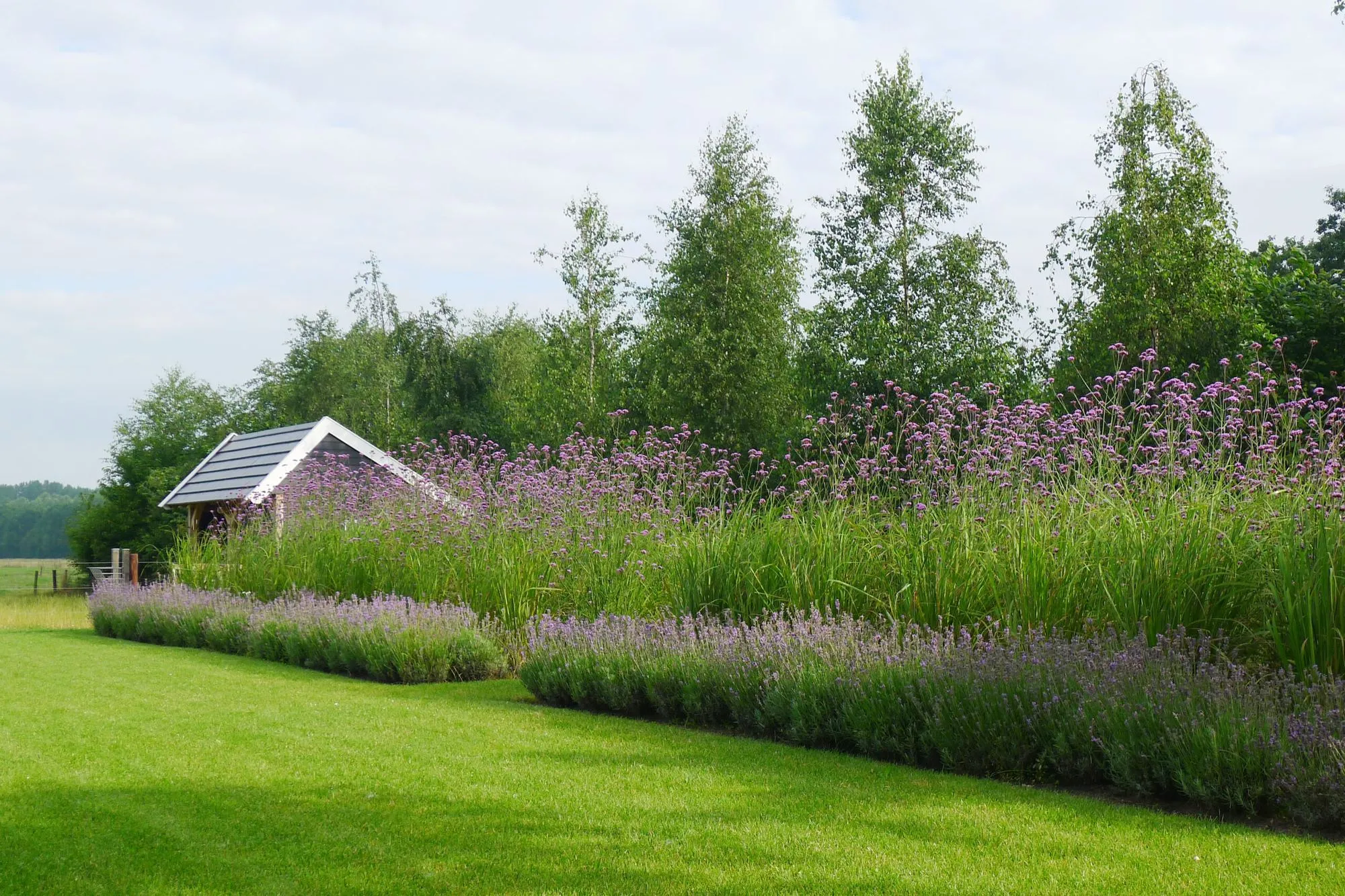 Langgerekte waterpartij met reflectie van de lucht en kleurrijke beplanting eromheen