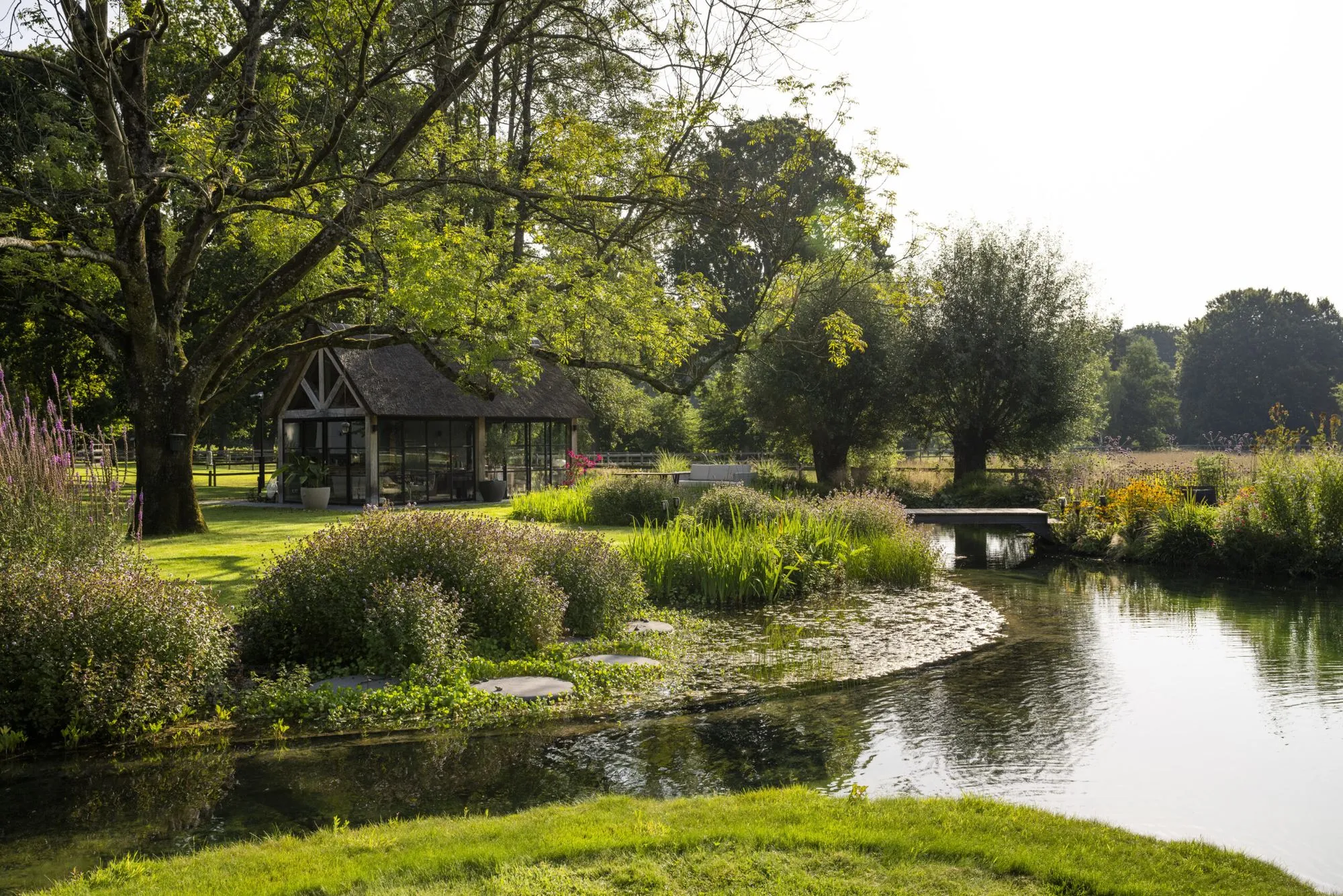 Landelijke tuin met vijver en rieten bijgebouw, aangelegd door Meeuwis de Vries Tuinen